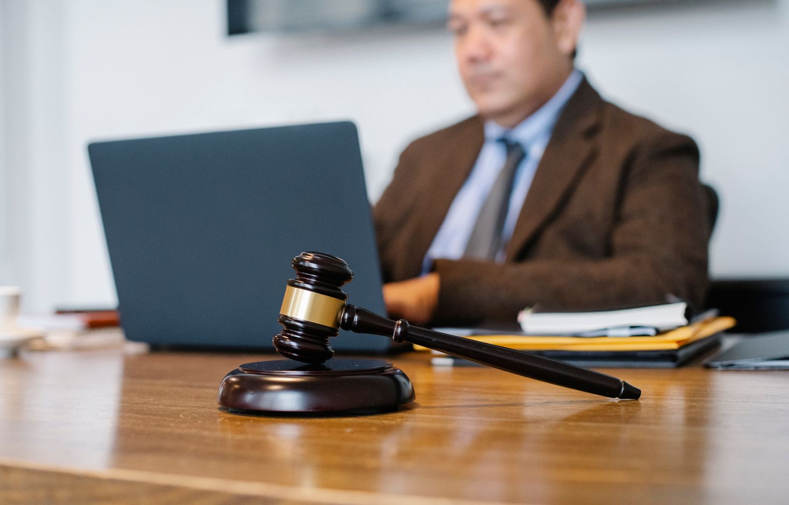 Attorney working at a desk with a laptop, legal folders, and a gavel in the foreground