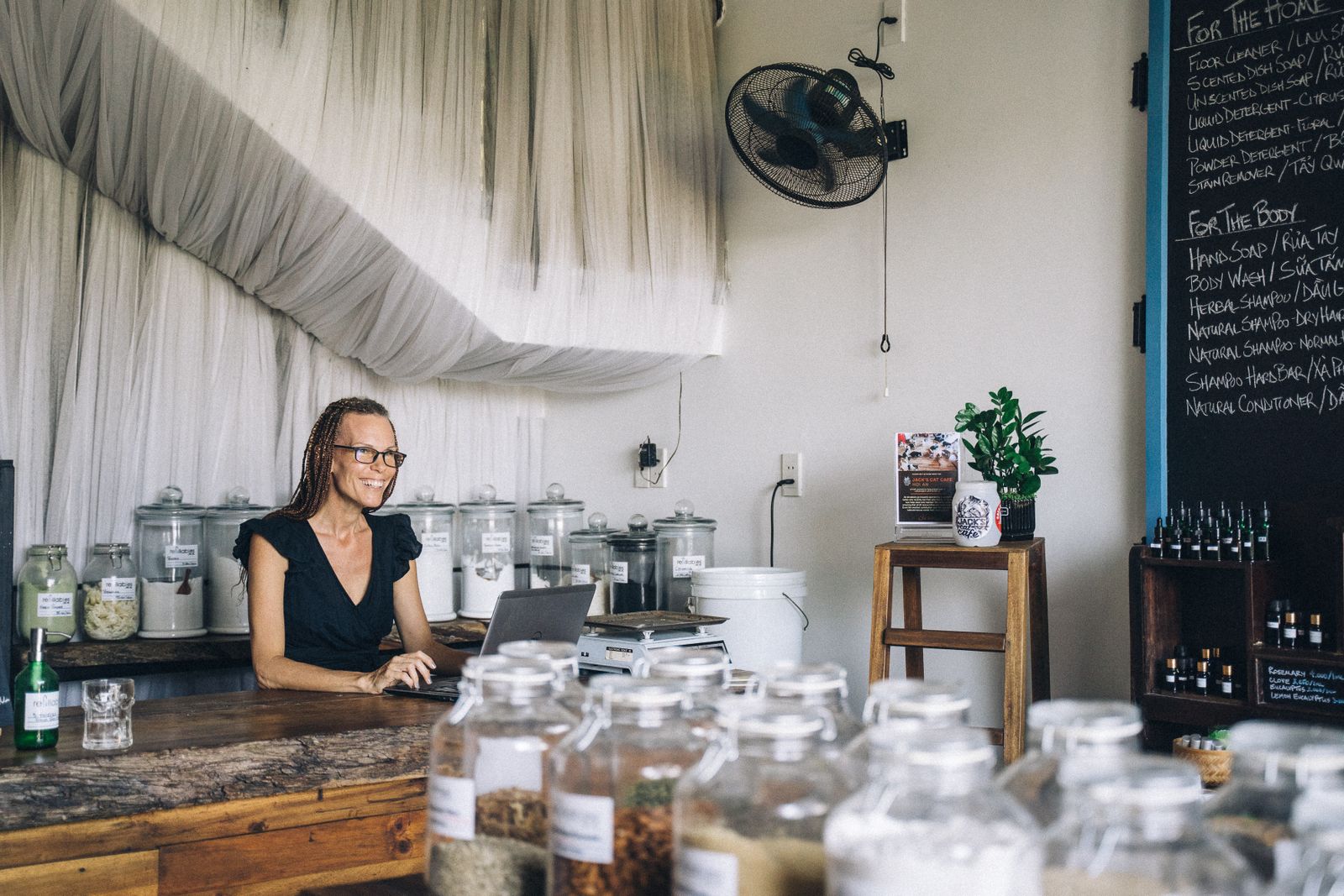 Small business owner working on a laptop behind the counter of her shop
