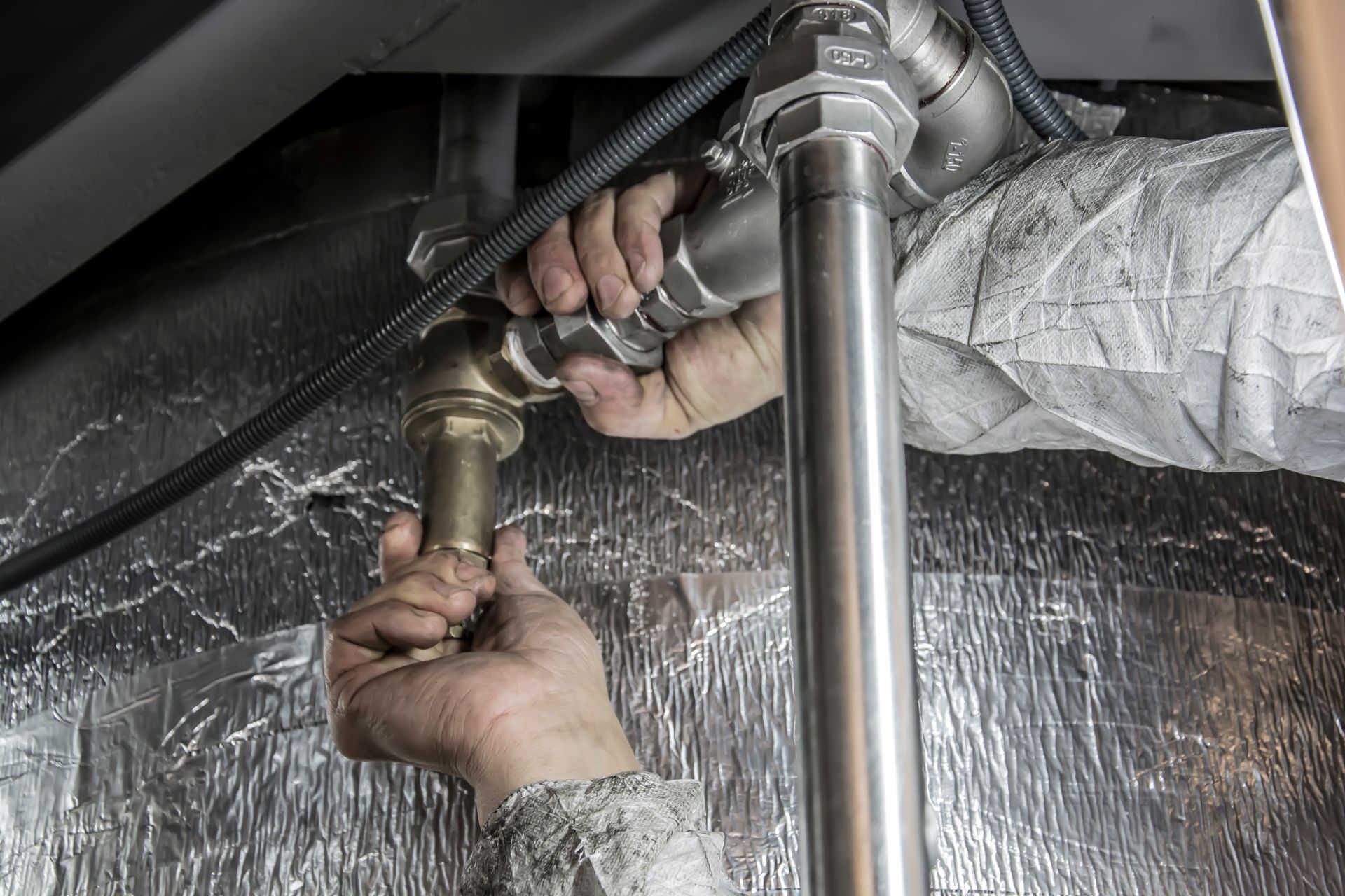 Close-up of a plumber's hands installing steel pipe fittings indoors